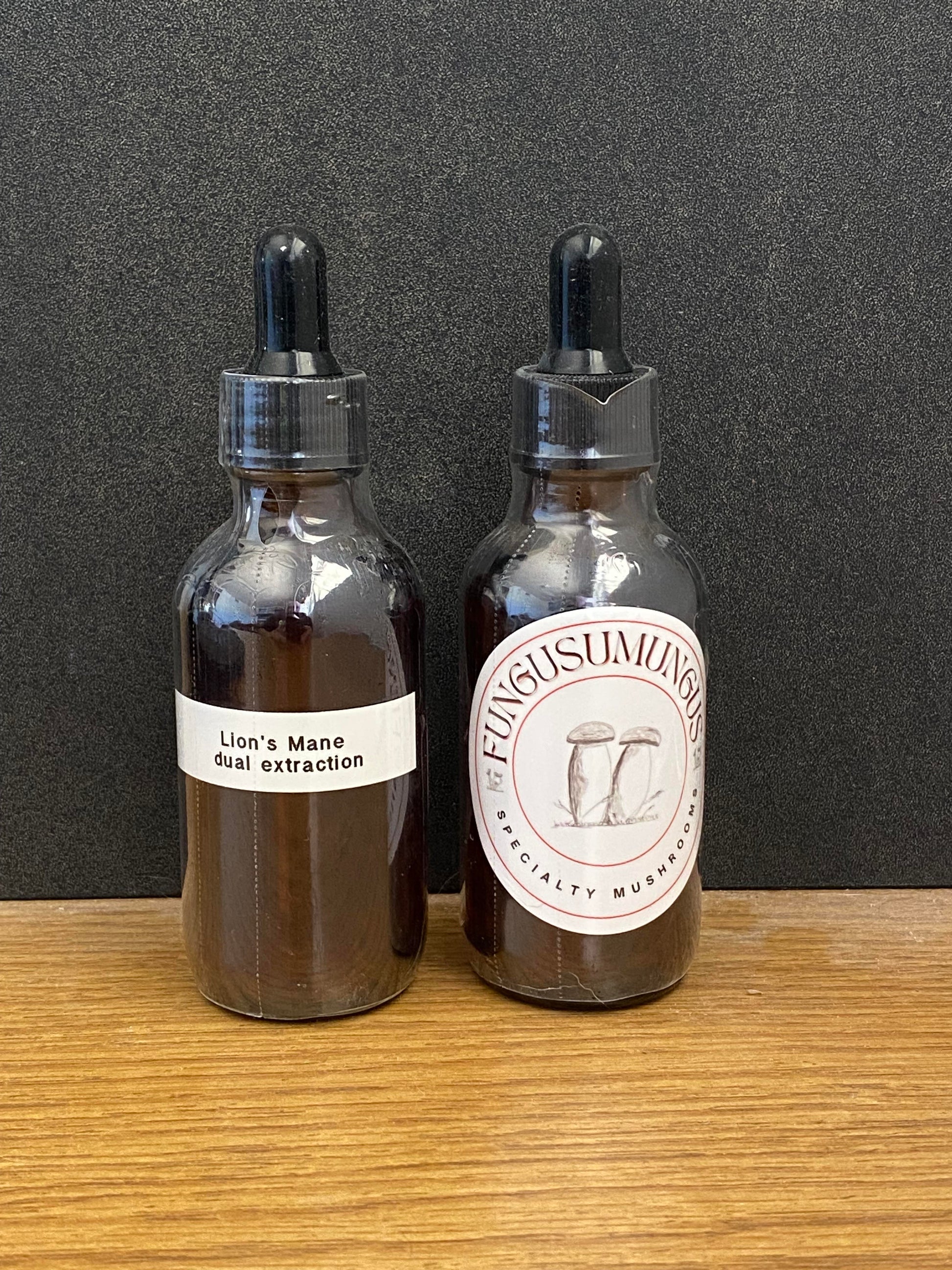Two glass bottles with dropper caps on a wooden surface against a dark background